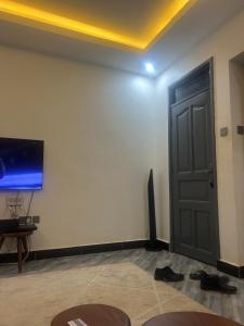 a room with a door and a tv and shoes at AJ Space in Kampala