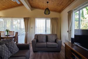 a living room with a couch and a tv at The Mook Mollymook in Mollymook
