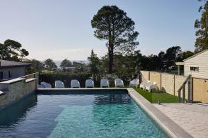 a swimming pool with chairs in a yard at The Mook Mollymook in Mollymook