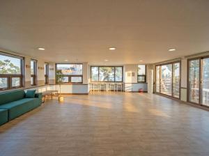 a large room with a couch and tables and windows at Onseul Pension Busan in Busan