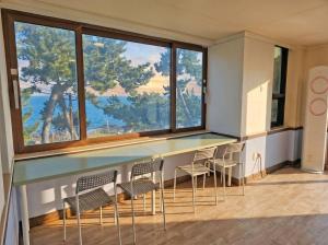 a room with chairs and a counter with a large window at Onseul Pension Busan in Busan