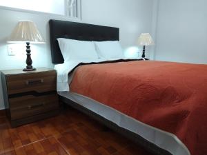 a bed with a red blanket and two lamps on a night stand at Gran Tonantzin in San Martín de las Pirámides