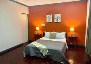 a bedroom with a large bed with an orange wall at Luca in San José