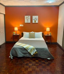 a bedroom with a large bed with an orange wall at Luca in San José