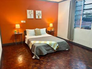 a bedroom with a bed with an orange wall at Luca in San José