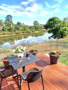 a table and chairs on a wooden deck next to a river at BIG4 Stratford Caravan Park in Stratford