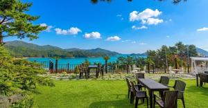 a lawn with tables and chairs and a view of a lake at Gaza Spa Pool Villa Yeosu in Yeosu