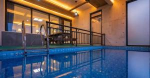 a swimming pool with a table and chairs in it at Gaza Spa Pool Villa Yeosu in Yeosu