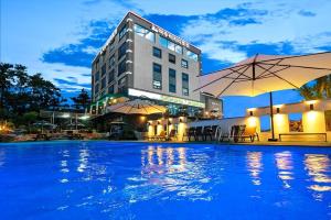 a hotel with a swimming pool in front of a building at Oceanview Spa Beach Resort Yeosu in Yeosu