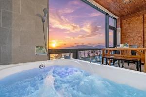 a bath tub with a view of the sunset at Oceanview Spa Beach Resort Yeosu in Yeosu