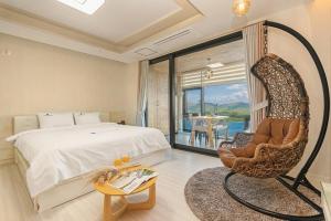 a bedroom with a bed and a chair and a window at Oceanview Spa Beach Resort Yeosu in Yeosu