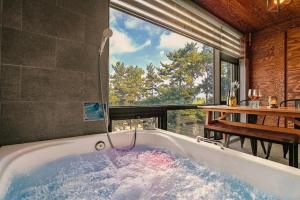 a bath tub in a room with a large window at Oceanview Spa Beach Resort Yeosu in Yeosu +23 photos