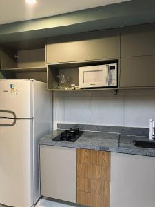a kitchen with a white refrigerator and a microwave at risorte eco carneiros in Tamandaré