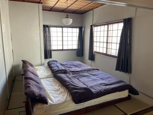 a bed in the corner of a room with two windows at 十度-jude- in Osaka