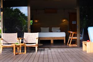 a bedroom with a bed and two chairs on a deck at Serenity Sands Island Glamping in Bounty Island