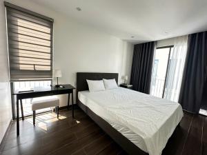 a bedroom with a bed and a desk and windows at Villa Florent in Thanh Hóa