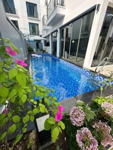 a swimming pool in front of a building with flowers at Villa Florent in Thanh Hóa