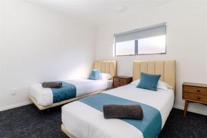 a room with two beds and a window at Te Awa Suites in Hamilton