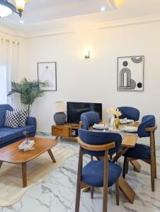 ein Wohnzimmer mit einem Tisch und blauen Stühlen in der Unterkunft Meublés tout confort à Makepe - Immeuble KOLA - Groupe Électrogène in Douala