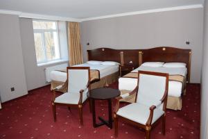 a hotel room with two beds and a table and chairs at White House Hotel in Ulaanbaatar