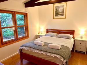 a bedroom with a bed with two pillows and two windows at 2 bedroom Guesthouse in the Centre of Noojee in Noojee