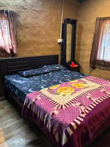 a bedroom with a bed with a colorful blanket on it at Amber Mount Resorts in Kanthalloor