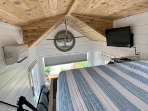 a bedroom in a tiny house with a flat screen tv at The Eagle’s View (Tiny Home 4) in Bellevue
