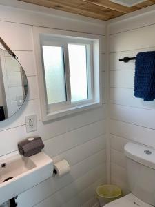 a white bathroom with a sink and a mirror at The Eagle’s View (Tiny Home 4) in Bellevue