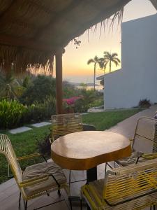 a table and chairs under a porch with the sunset at Casa Palma in Santa Cruz Huatulco