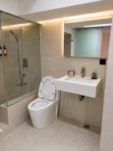 a bathroom with a toilet and a sink and a mirror at The E-Hotel Makati in Manila