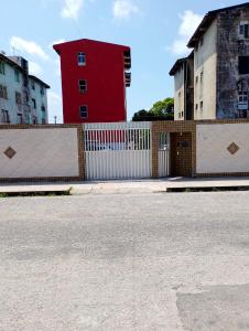 a red building with a white fence in front of buildings at Quarto Soleil in Aracaju +3 photos