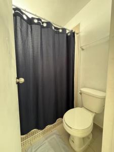 a bathroom with a toilet and a black shower curtain at Equipped house in Salinas industrial zone in Ciudad Satelite del Norte