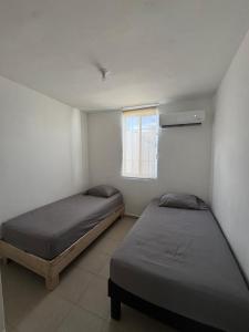 two beds in a room with a window at Equipped house in Salinas industrial zone in Ciudad Satelite del Norte