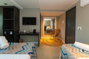 a bedroom with two beds and a desk and a chair at Pousada de Charme Refugio da Villa - Pé na Areia in Porto De Galinhas