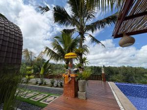 a house with a wooden deck with a palm tree at Artala Villa & Restaurant in Besakih +12 photos