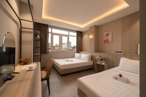 a hotel room with two beds and a desk at The Cozy Hotel in Ho Chi Minh City