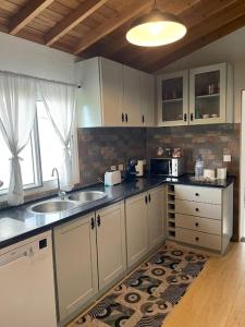a kitchen with white cabinets and a sink and a window at Rustica Ocean View House in Bretanha