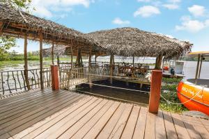 a wooden deck with a straw umbrella and a boat at Lake Resort Bolgoda in Wadduwa