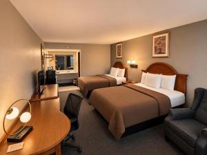 a hotel room with two beds and a desk at Ozark Inn & Suites in Ozark