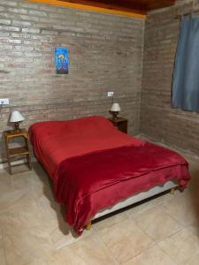 a bedroom with a large red bed with two tables at Cabañas Frago in Villa Amancay