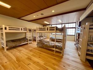 a room with several bunk beds in a room with wooden floors at ヨゴダステイアンドリトリート Yogoda Stay & Retreat in Ina