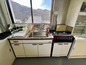 a kitchen with a sink and a stove and a window at ヨゴダステイアンドリトリート Yogoda Stay & Retreat in Ina +10 photos