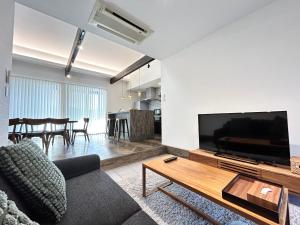 a living room with a couch and a flat screen tv at 南アルプスを望むサウナ付き宿,田園風景,全室エアコン,バーベキュー可 in Hokuto