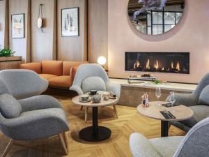 a living room with a couch and chairs and a fireplace at Novotel Cambridge North in Cambridge