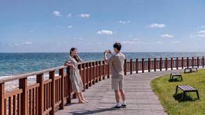 a man taking a picture of a woman on a boardwalk at Yangyang J Ocean View in Yangyang +2 photos
