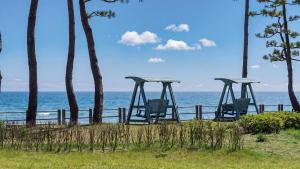 three empty swings sitting next to the ocean at Yangyang J Ocean View in Yangyang