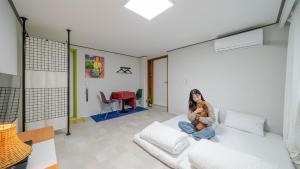 a woman sitting on a white couch holding a dog at Yangyang J Ocean View in Yangyang