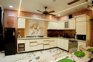 a kitchen with white cabinets and a painting of a woman at The White Lilly in Noida