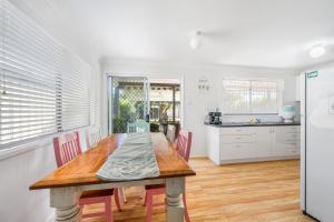 a kitchen and dining room with a wooden table and chairs at Mirrabooka in Lake Cathie