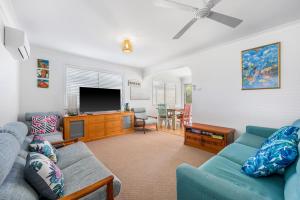 a living room with a couch and a flat screen tv at Mirrabooka in Lake Cathie +11 photos